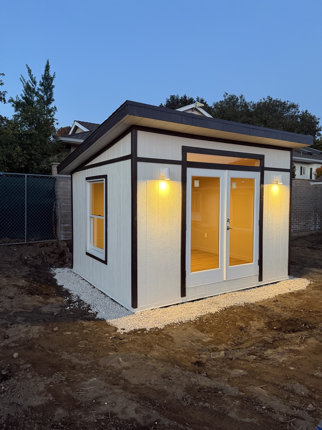 White 12 by 10 ft studio with dark trim glowing at dusk