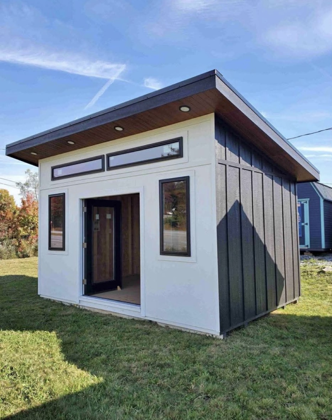White and charcoal 15 by 8 ft creative studio on a green lawn